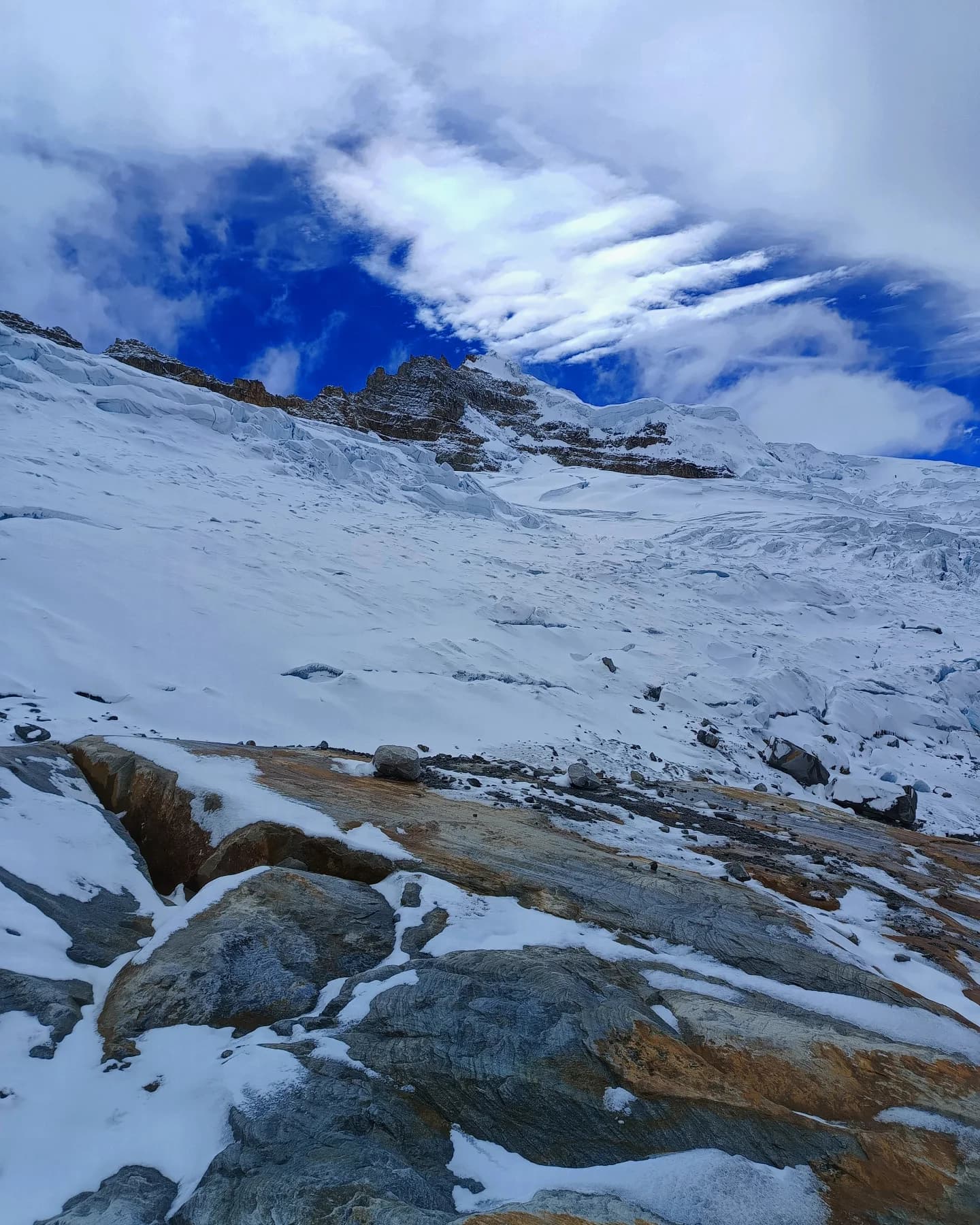 Ladera y planicie cubierta de nieve con pequeñas rocas visibles.