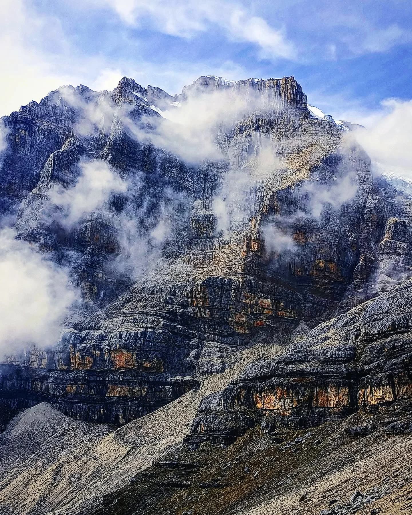 Pared rocosa iluminada por el sol con texturas anaranjadas.