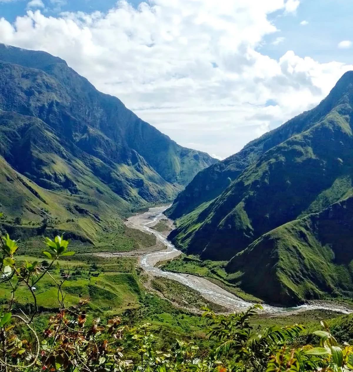 Valle amplio con un río serpenteante entre montañas verdes.