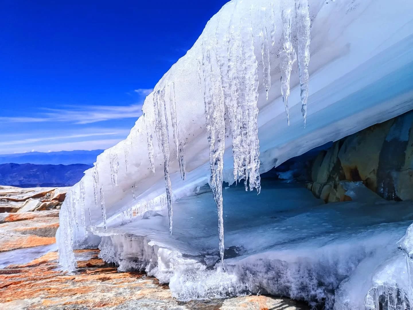 Borde de hielo con formaciones colgantes (estalactitas de hielo) y textura azulada.