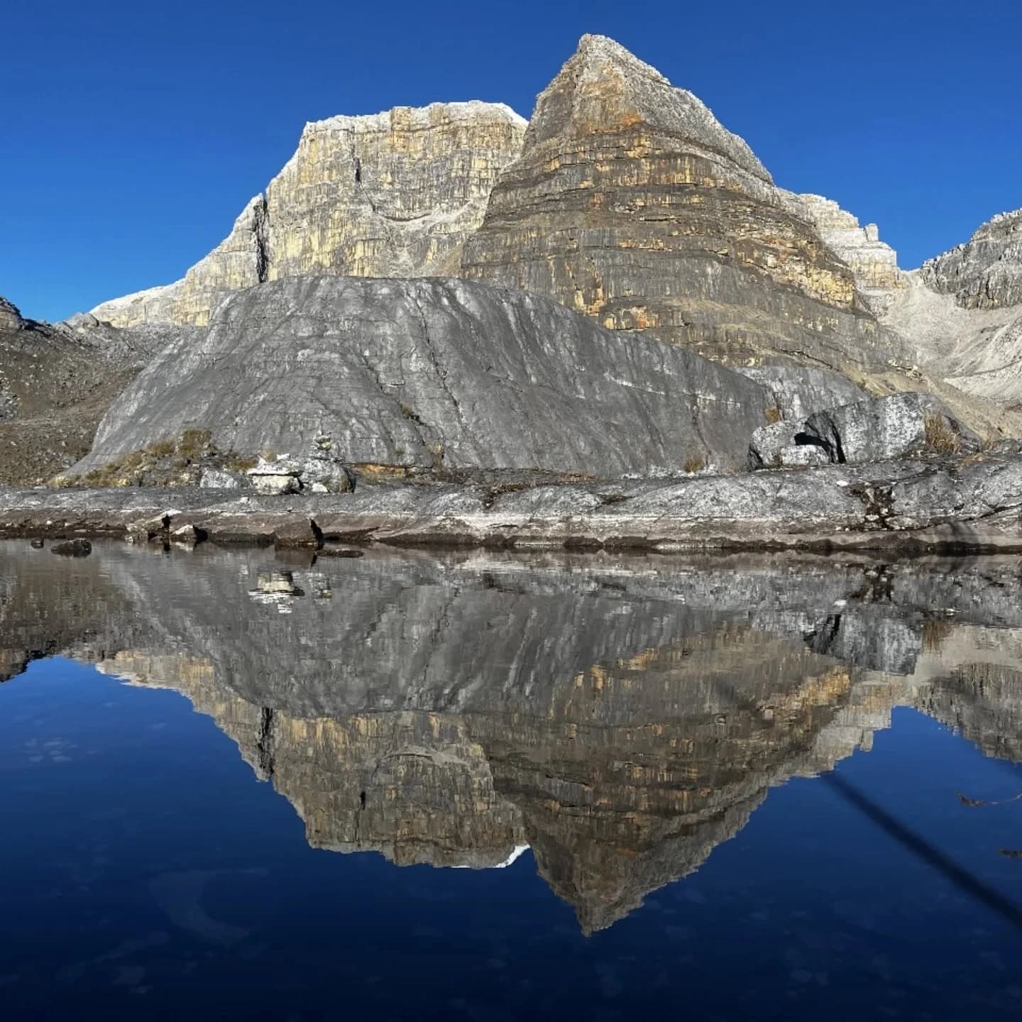 Reflejo de una pared rocosa en una laguna tranquila, formando un espejo en el agua.